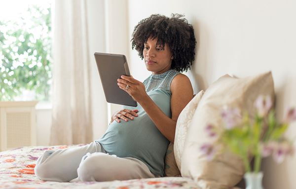 pregnant woman reads tablet in bed pregnant woman reads tablet in bed